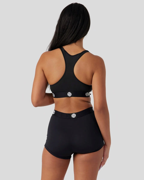 Black sports bra and shorts set with circular logo details, shown from back view.