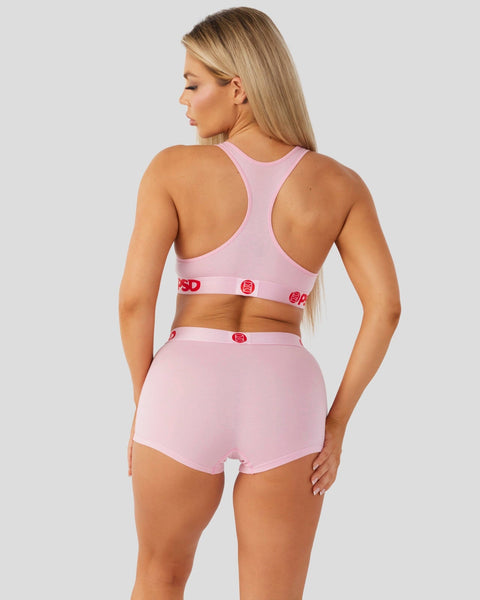 Pink racerback sports bra and matching briefs with red logo waistband detail.