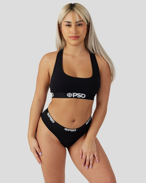 Woman wearing black halter sports bra and matching briefs with PSD branding.
