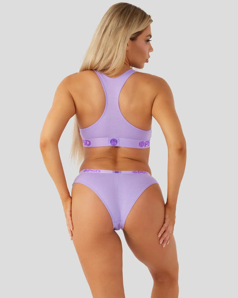 Woman wearing lavender racerback sports bra and matching briefs with logo waistband, shown from back view.
