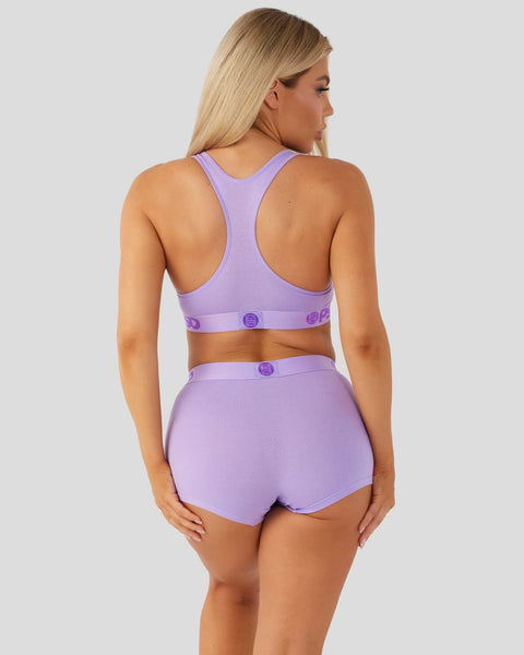 Woman wearing a lavender racerback sports bra and matching shorts with snap closures, shown from behind.