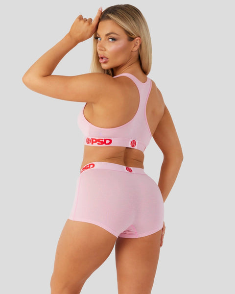 Woman wearing pink sports bra and matching briefs with red branding, shown from back view.