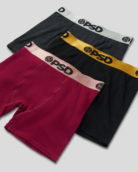 Three boxer briefs in burgundy, black, and charcoal with metallic gold, pink, and silver waistbands.
