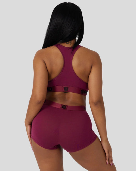 Deep burgundy racerback sports bra and matching shorts with black buckle closures, shown from back view.