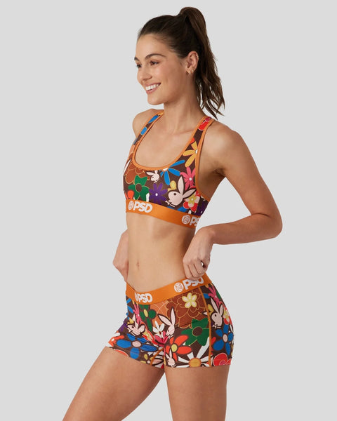Woman wearing colorful floral-patterned sports bra and shorts with orange PSD waistband.