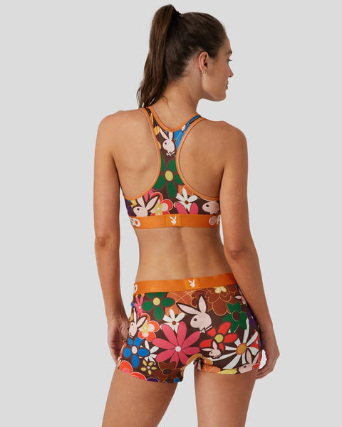 Woman wearing Playboy Funk two-piece swimsuit with colorful floral and bunny print pattern, shown from back.