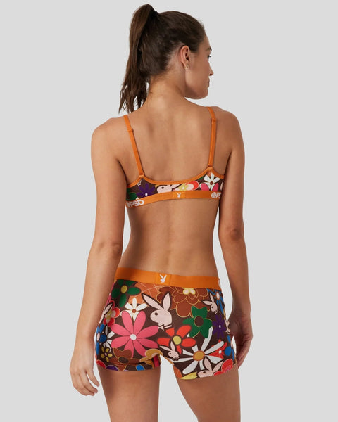 Woman wearing orange-trimmed bikini top and matching shorts with colorful floral and bunny print, shown from back.