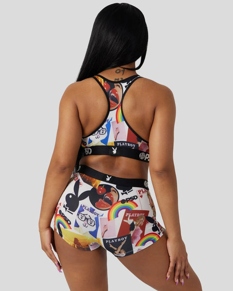 Woman wearing Playboy-branded sports bra and shorts with colorful cover artwork, rainbow, and bunny logo prints, viewed from 
