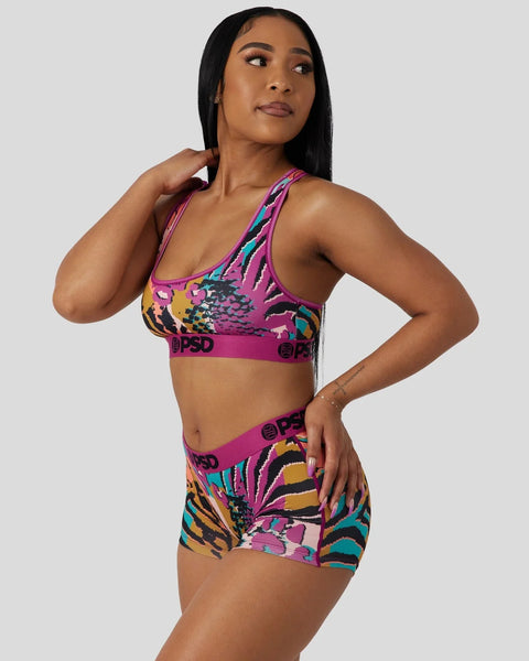 Woman wearing purple sports bra and matching shorts with multicolored animal print pattern and branded waistband.