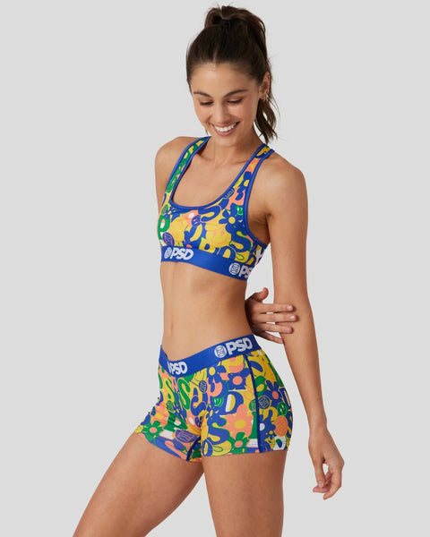 Woman wearing blue, yellow, and green patterned sports bra and matching shorts with PSD branding.