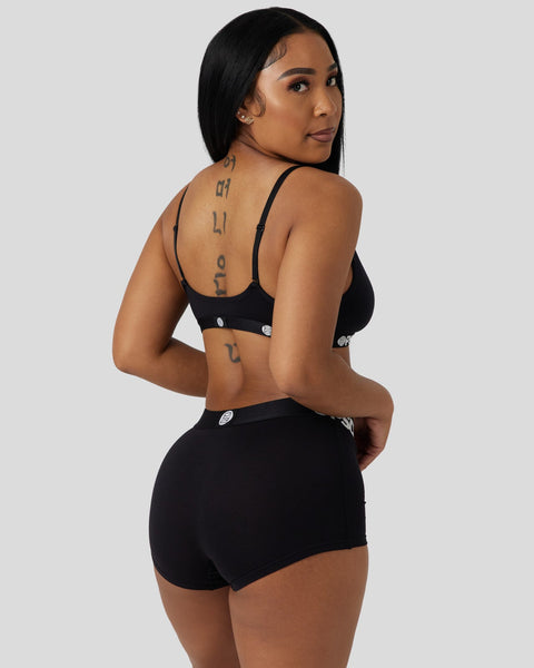 Woman wearing black modal bra and shorts with silver-toned hardware details, shown from behind.