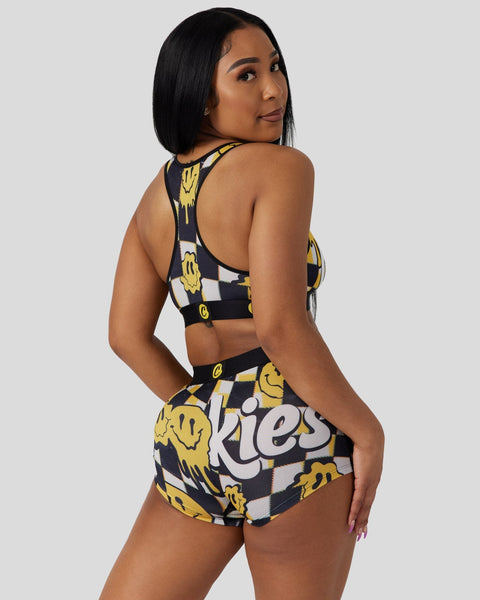 Woman wearing a two-piece set with yellow smiley face pattern on black and white checkered background.