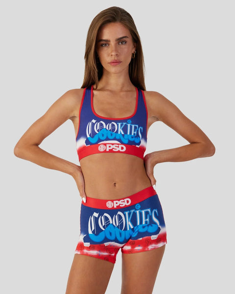 Woman wearing blue, red, and white Cookies-branded sports bra and shorts set with PSD waistband.