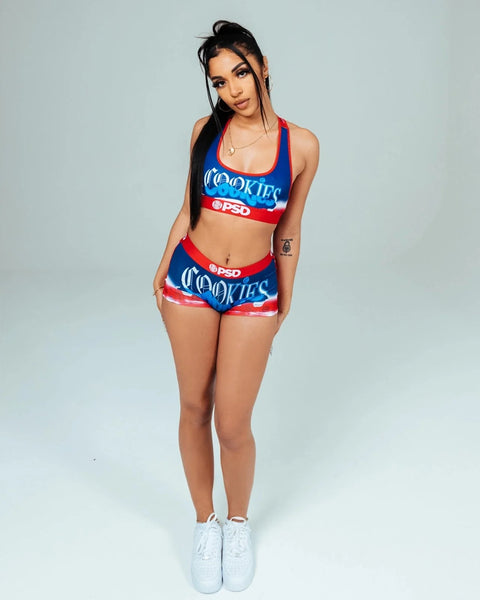 Woman wearing blue and red Cookies sports bra and shorts set with PSD branding.
