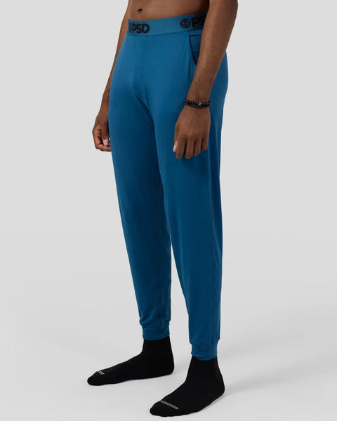 Teal lounge pant with branded waistband and tapered cuffs, shown on model wearing black socks.