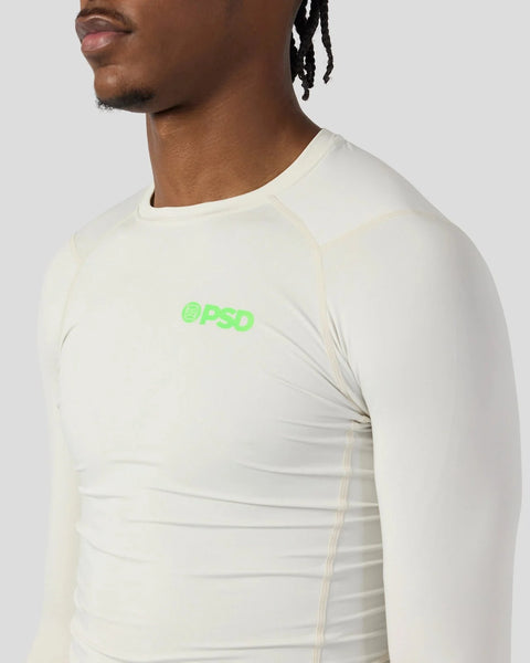 Cream-colored long sleeve compression shirt with green logo on chest, shown on male model.