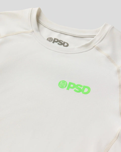Cream long-sleeve compression tee with PSD branding in gray at neckline and neon green logo on chest.