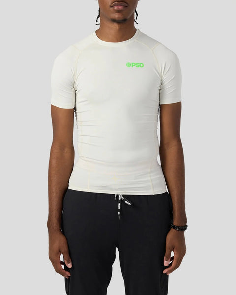 Cream short-sleeve compression tee with green logo on chest, fitted silhouette.