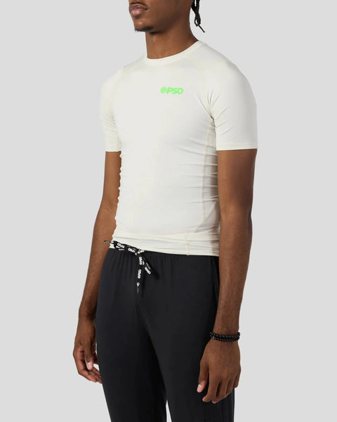 Cream short-sleeve compression tee with neon green branding on chest, fitted to torso.