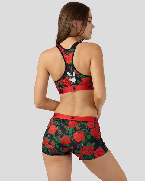Woman wearing black sports bra and shorts with red rose and white Playboy bunny print pattern.