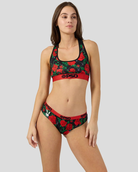 Woman wearing black sports bra and briefs with red rose pattern and red elastic bands with PSD branding.