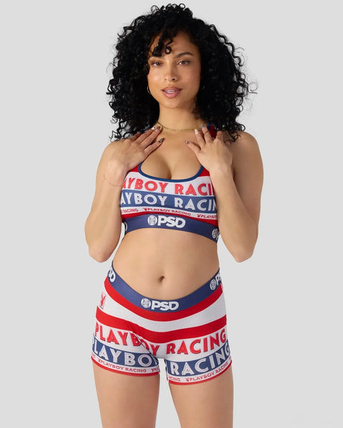 Woman wearing red, white, and navy Playboy Racing sports bra and shorts set with PSD branding.