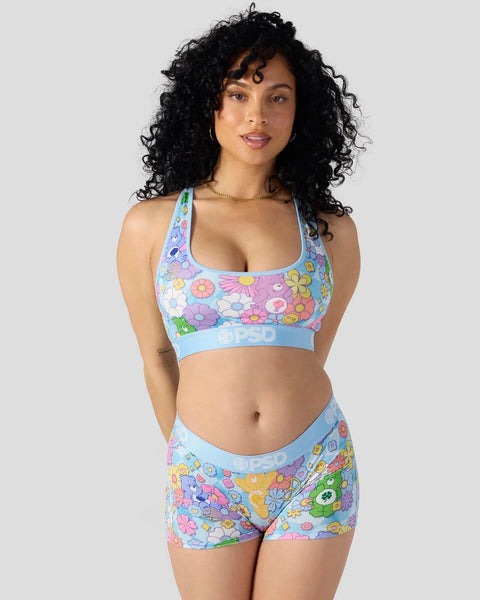 Woman wearing multicolored Care Bears floral sports bra and matching shorts with blue trim.
