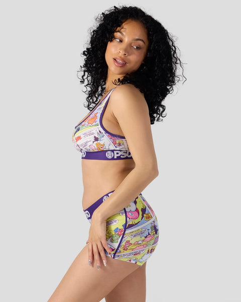 Woman wearing Care Bears comic print sports bra and shorts set with purple trim.