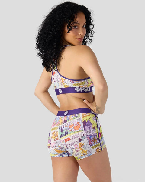 Woman wearing Care Bears comic-print sports bra and shorts set with purple trim and branding.