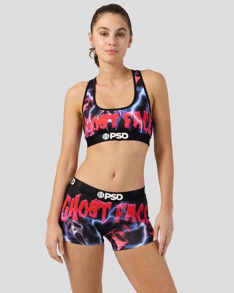 Woman wearing black sports bra and shorts with red and blue lightning bolt print and PSD branding.