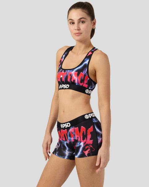 Woman wearing black sports bra and shorts with red and blue lightning bolt graphic print and PSD branding.
