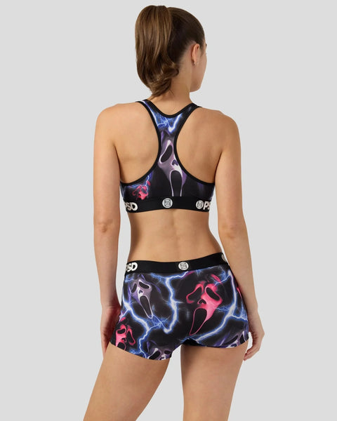 Woman wearing black sports bra and shorts with blue and pink ghost face print, shown from back view.