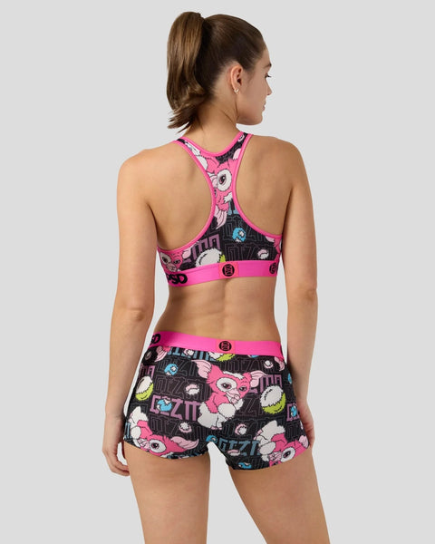 Woman wearing pink and black Gizmo-patterned sports bra and shorts set with neon accents, shown from back view.