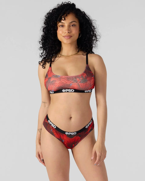 Woman wearing red and black patterned sports bra and briefs set with branded elastic waistband.
