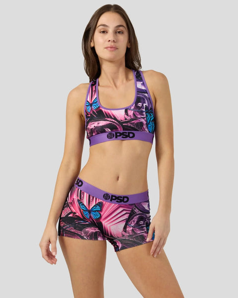 Woman wearing purple and pink patterned sports bra and shorts set with butterfly and geometric designs.