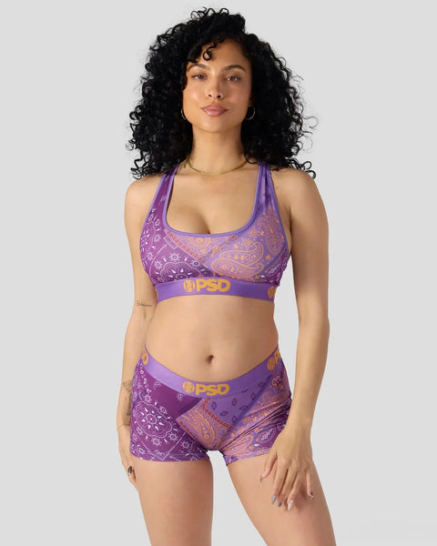 Purple bandana-patterned sports bra and shorts set with gold accents on model.