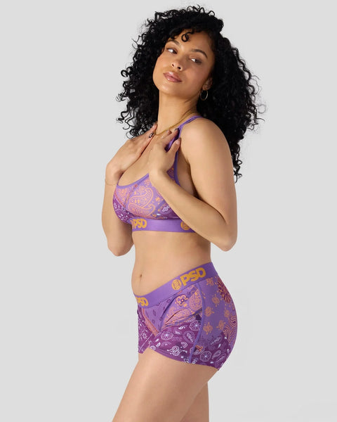 Purple bandana-print sports bra and shorts set with paisley design and brand lettering.