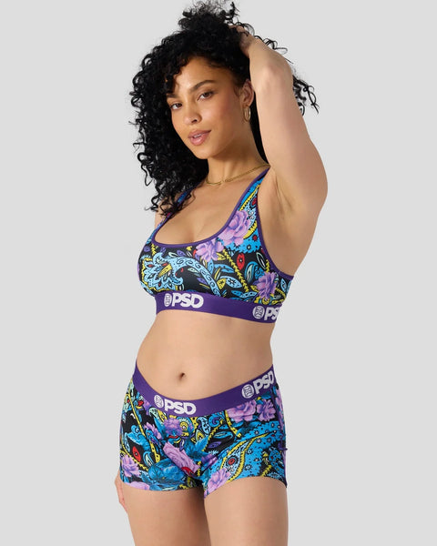 Purple sports bra and shorts set with multicolored paisley and floral pattern throughout.