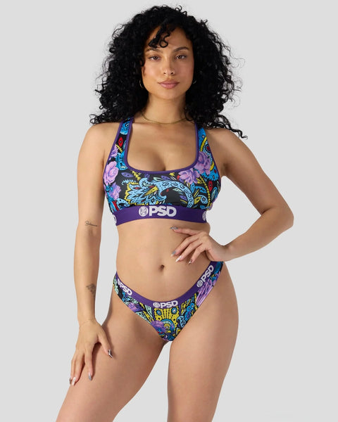 Colorful paisley print sports bra and bikini bottom set with purple waistband and logo detail.