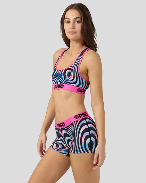 Woman wearing neon pink sports bra and shorts with holographic swirl pattern in blue, purple, and black stripes.