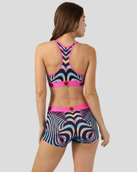 Woman wearing neon pink sports bra and matching shorts with black and blue holographic geometric stripe pattern throughout.