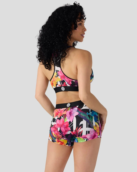Black sports bra and shorts with colorful floral print on dark background, shown from back view.