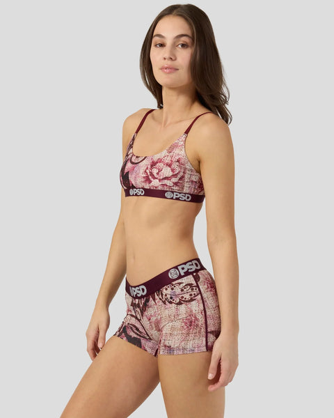 Woman wearing burgundy jacquard floral sports bra and matching shorts with branded elastic waistbands.