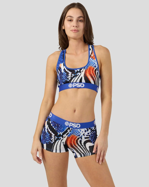 Woman wearing blue, white, orange and black patterned sports bra and shorts set with PSD branding.