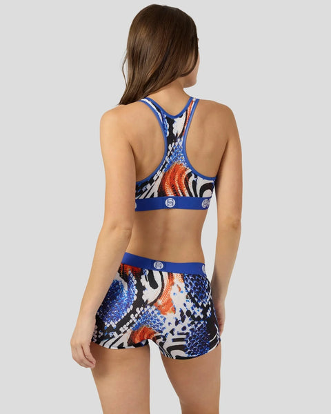 Woman wearing blue sports bra and shorts with snake scale pattern in blue, orange, white and black.