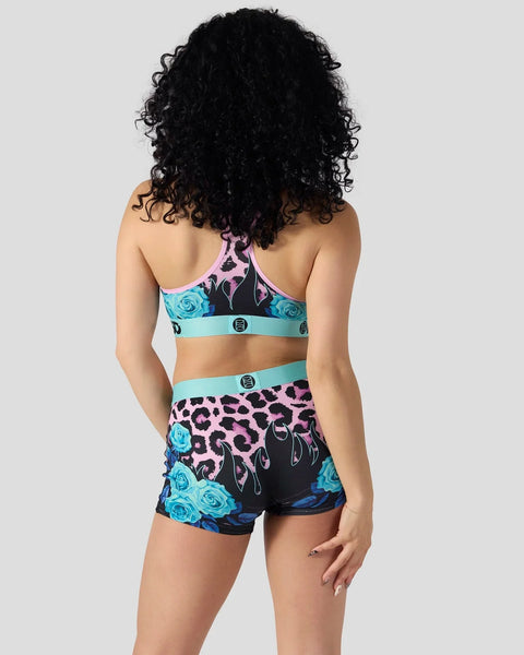 Two-piece athletic set with leopard print, floral roses, and turquoise bands on sports bra and shorts.