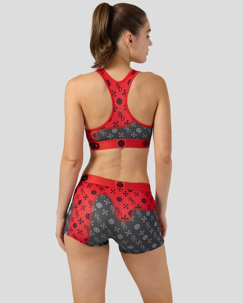 Red and gray sports bra and shorts set with geometric logo pattern shown from back view on model.