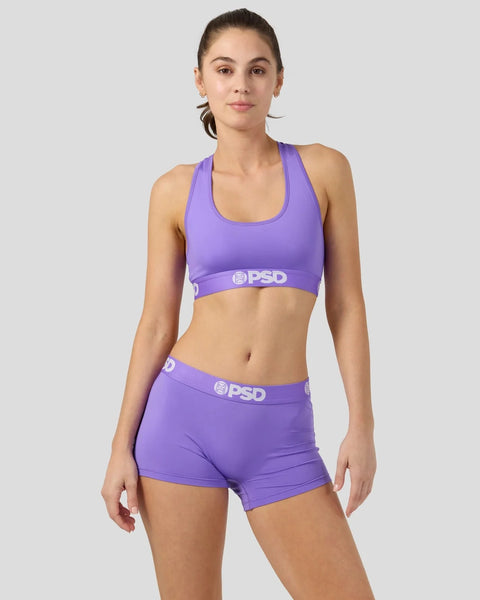 Woman wearing purple sports bra and matching shorts with PSD branding.