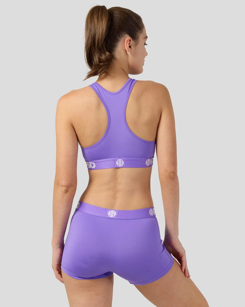 Purple sports bra and shorts set with branded waistband details, shown from back view on model.