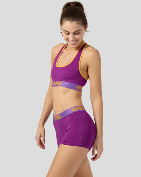 Purple and yellow sports bra and shorts set with branded waistband detail.